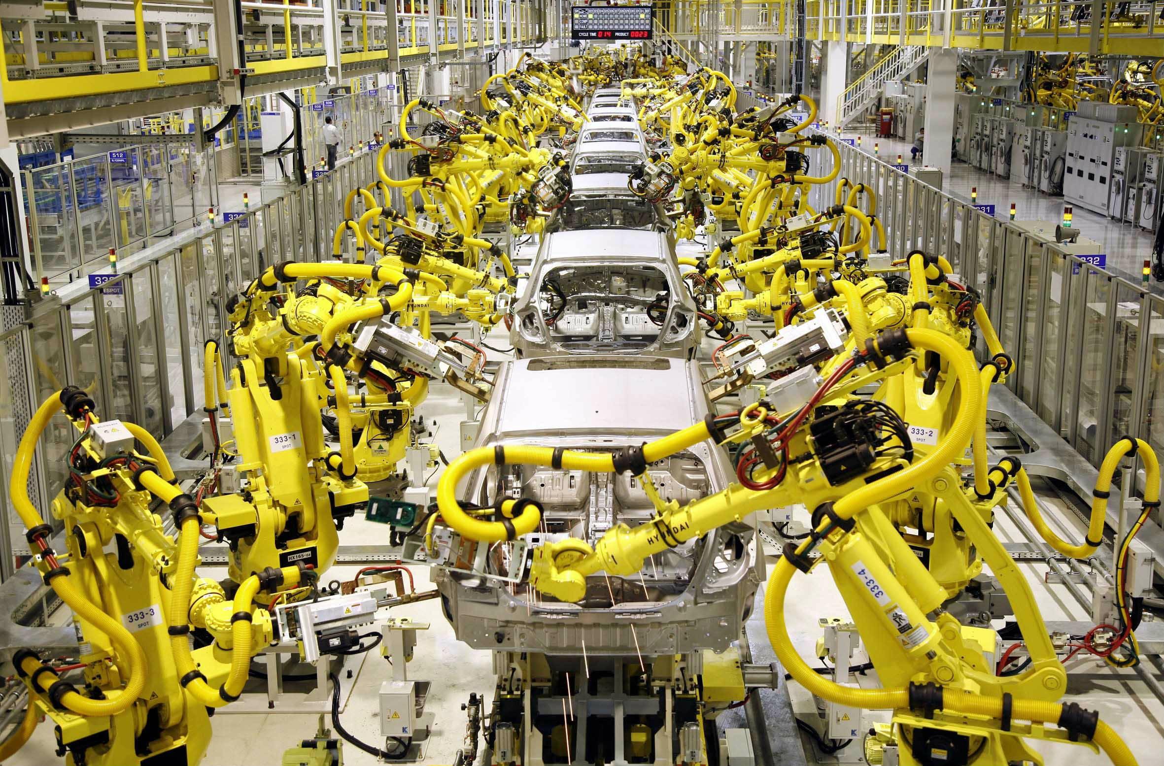A car assembly line staffed by rows of yellow industrial robots.