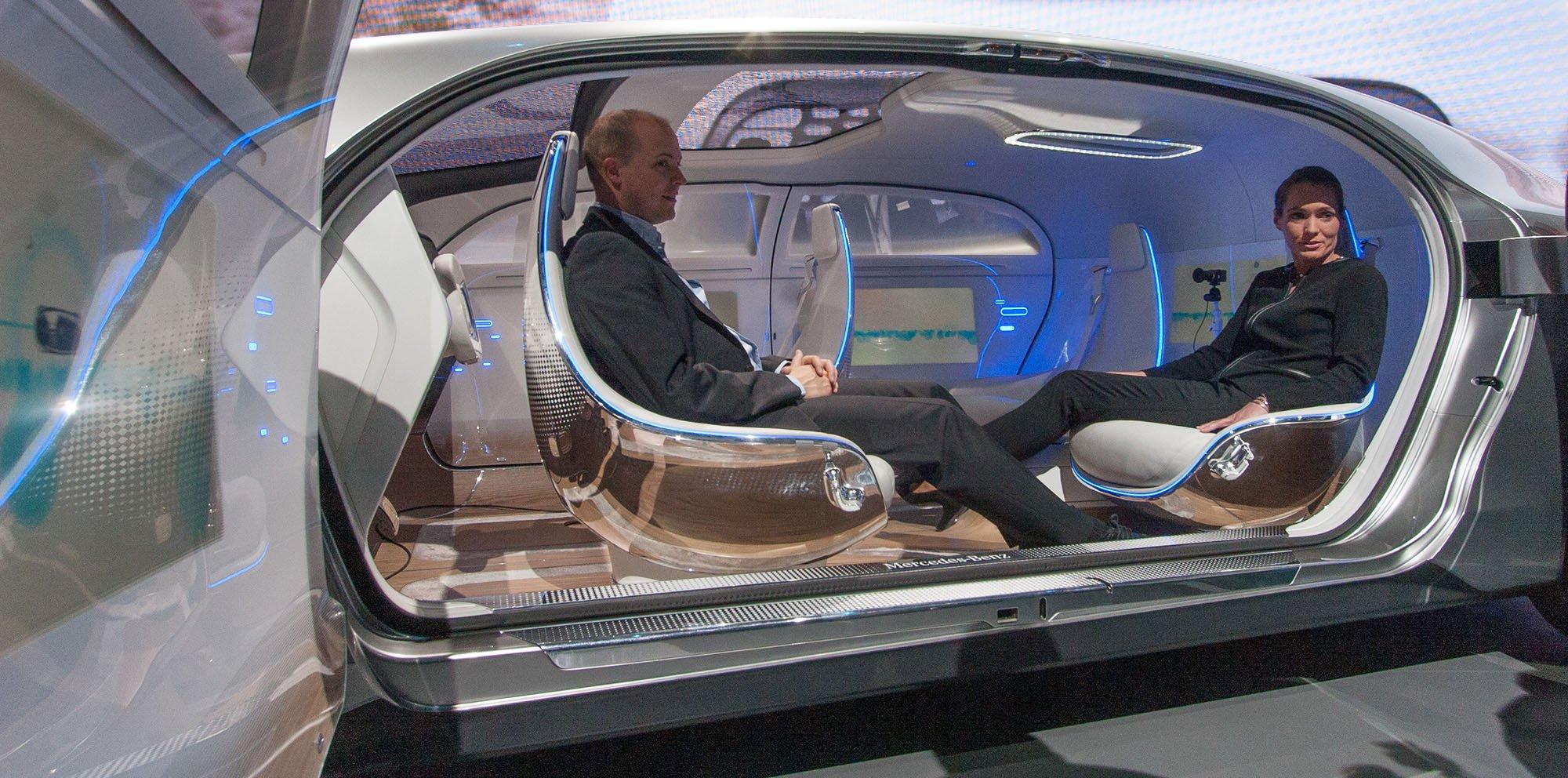The lounge-like interior of a self-driving concept car, two people seated facing each other.