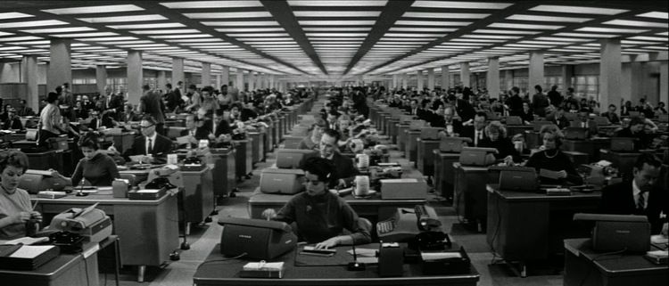 A vast mid-century office floor filled with rows of clerks at typewriters and adding machines.